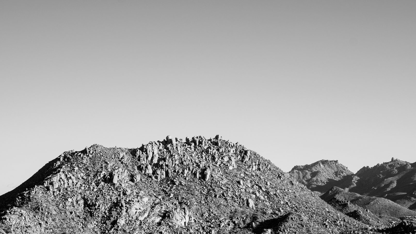A black and white image of foothills blemished by boulders.